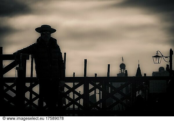 Düstere Stimmung  Gondoliere an Zaun stehend als Schattenriss im Gegenlicht  Venedig  Venetien  Italien  Europa