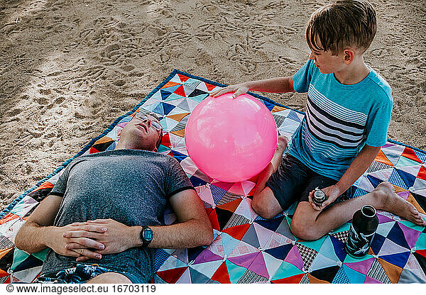 Dad and son relaxing on a picnic blanket on a sunny day