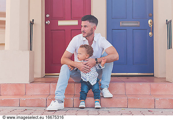 Dad and toddler sitting on the steps watching the street
