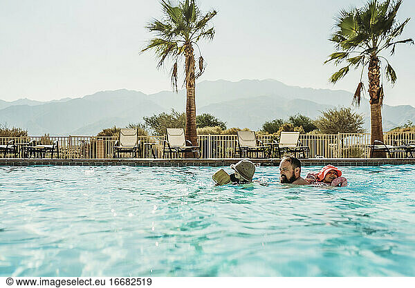Dad and young children swimming in large California pool on vacation