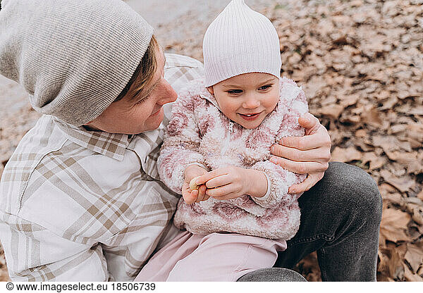 Dad holding his two-year-old daughter outdoors in spring