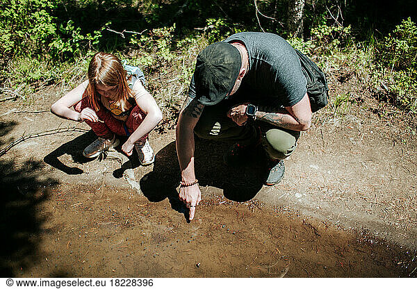 dad showing daughter tadpoles on a hike on a sunny day