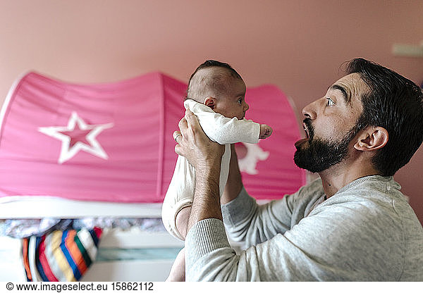 Dad with beard making faces at infant daughter