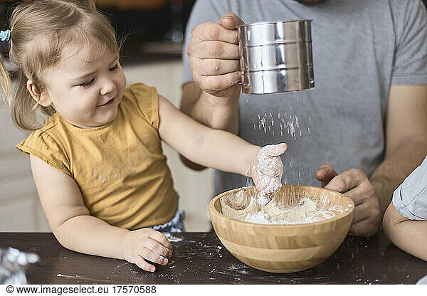 Daddy sifts the flour through a sieve