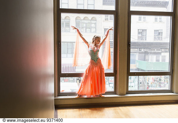 Dancer in dance studio. A woman posing at a window.