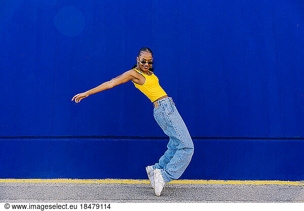 Dancer on tiptoes dancing by blue wall on footpath
