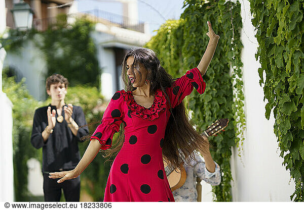 Dancer performing flamenco with guitarist near wall