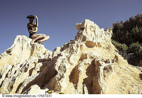 Dancer responds to sandstone cliffs over ocean in portugal summer