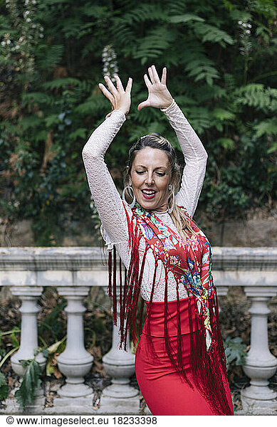 Dancer with arms raised doing flamenco in front of railing