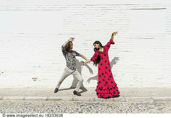 Dancers performing flamenco in front of white wall
