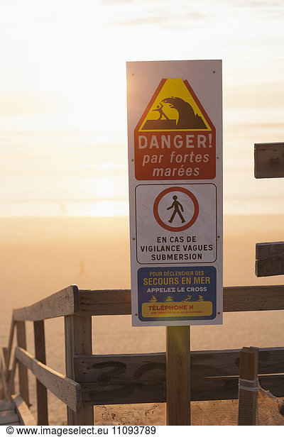 Danger information sign on the beach and stairs moving down to the beach