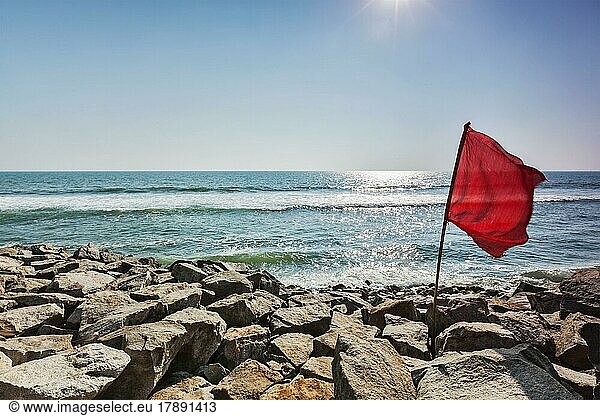 Danger  Red flag on rocky beach forbidding to swim