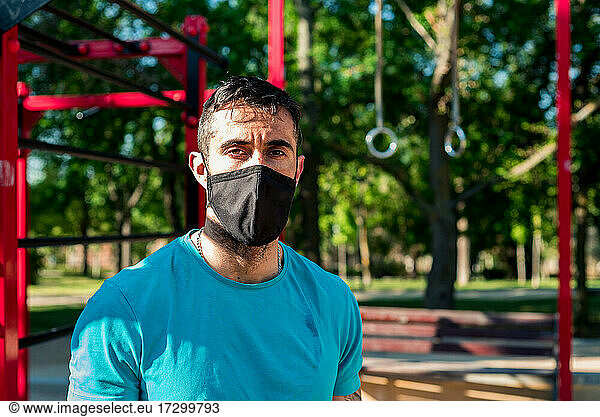 Dark-haired athlete with beard talking on mobile phone after training. Outdoor fitness concept.