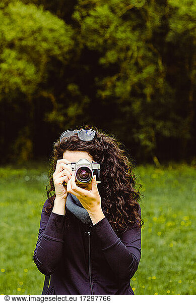 Dark-haired woman taking photos in the forest