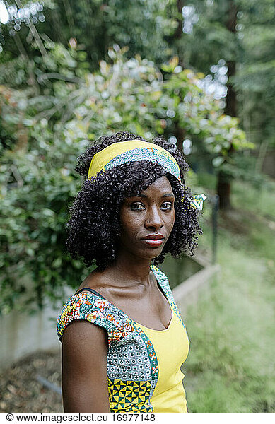 Dark skinned woman wearing African head band colorful dress outdoor