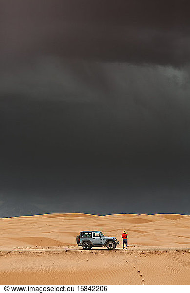 dark storms clouds and rain over sand dunes and jeep in utah desert