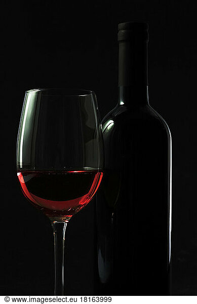 Dark studio shot of bottle and glass of red wine