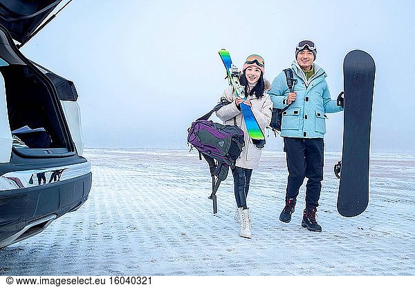 Das junge Paar auf einem Parkplatz mit Skiern