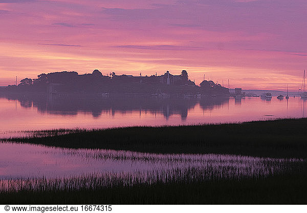 Das Licht der Morgendämmerung leuchtet in einem kräftigen Rosa über dem Biddeford Pool an der Küste von Maine.