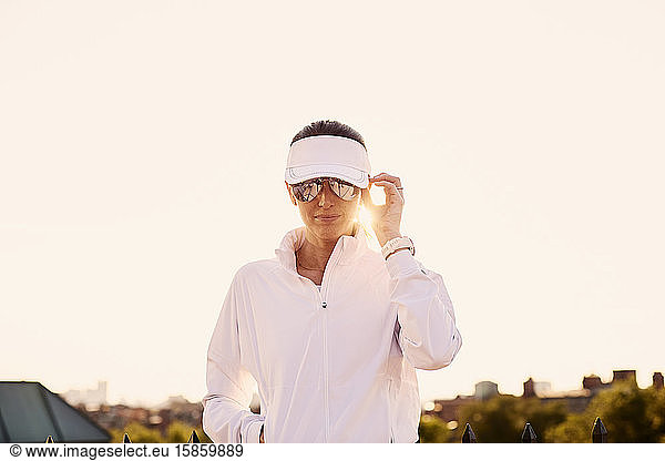 Das Porträt einer Frau in weißer Sportkleidung im Gegenlicht.