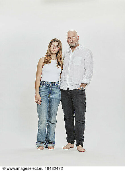 Daughter and father standing against white background