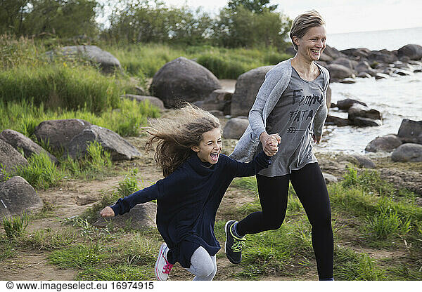 Daughter and mom run along the beach close-up.