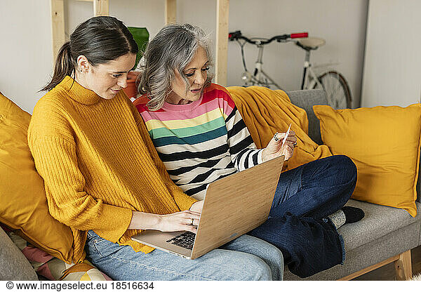 Daughter and mother shopping online with credit card on laptop