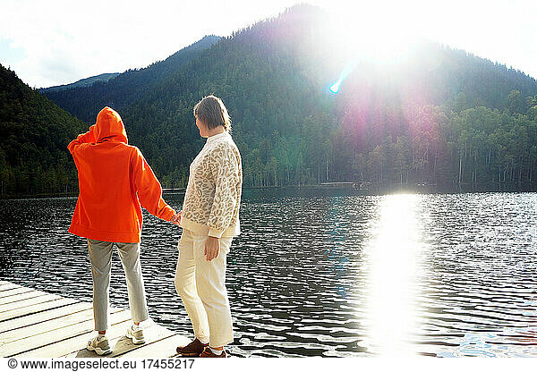 Daughter and mother walk on a wooden deck on Warm lakes