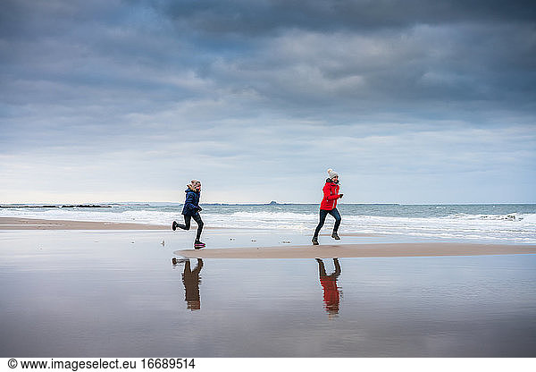 Daughter chasing her mother on the beach