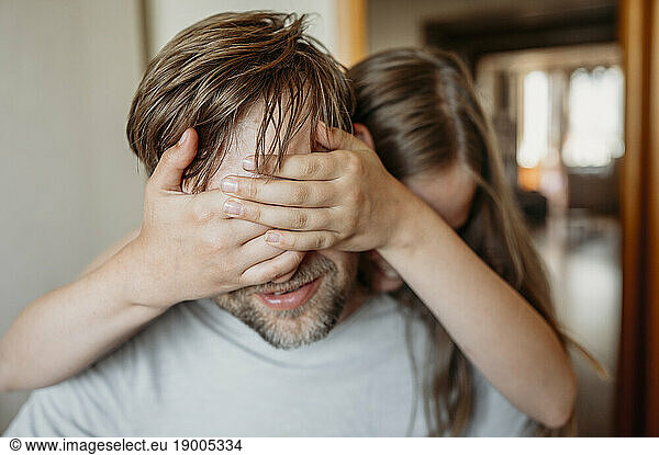 Daughter covering father's eyes with hand