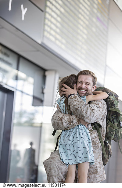 Daughter greeting and hugging soldier father at airport