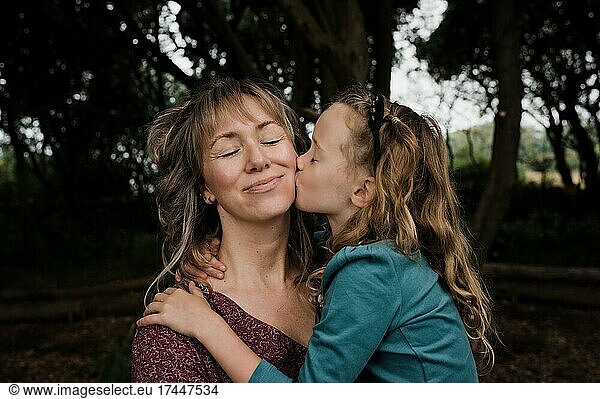 daughter kissing mother on the cheek whilst outdoors