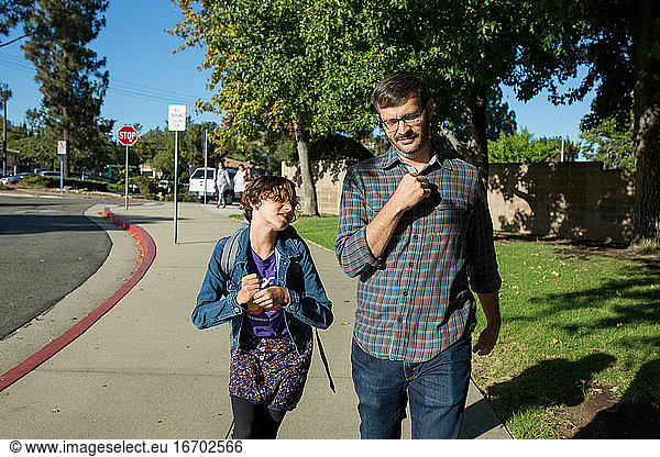 Daughter looks up at father as he walks with her to school