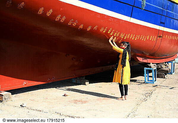 Daughter of boat owner performs puja on new boat by making hand prints along its hull prior to maiden launch  Vanakbara  Gujarat  India  Asia