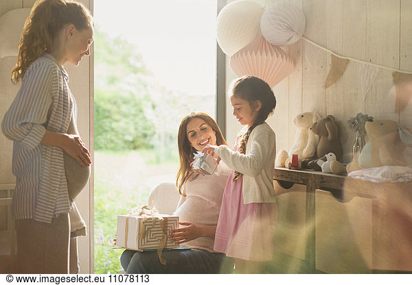 Daughter opening gift with pregnant mother