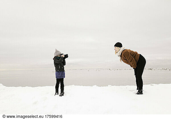 Daughter photographing mother through camera in winter