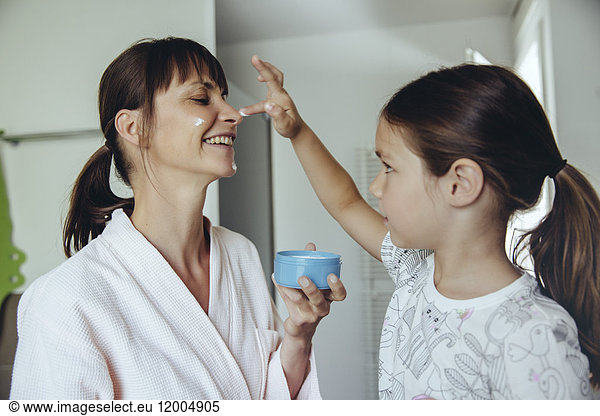 Daughter putting facial cream on mother?s face