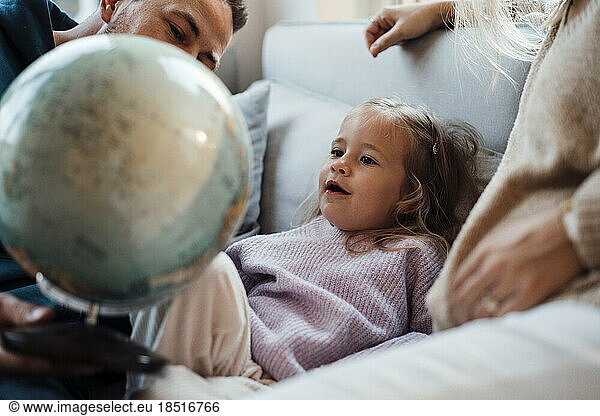 Daughter sitting with parents looking at globe in living room