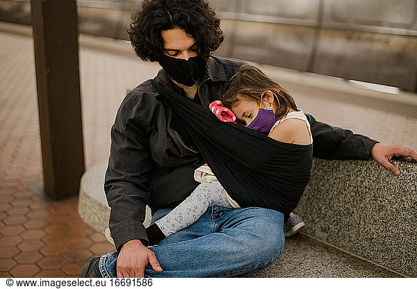 daughter sleeping in sling on dad wearing face masks