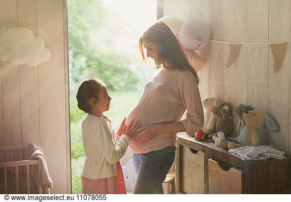 Daughter touching pregnant motherís stomach in nursery