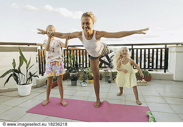 Daughters helping mother exercising on the terrace