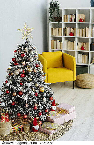 Decorated Christmas tree amidst gifts in living room at home
