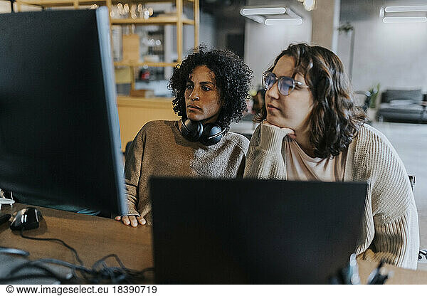 Dedicated female programmers using computer while working at desk in creative workplace