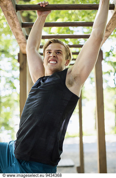 Dedicated man hanging on monkey bars at outdoor gym