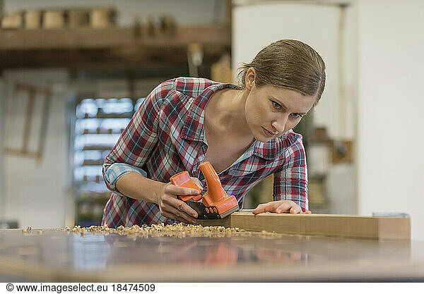 Dedicated trainee shaving wood in workshop