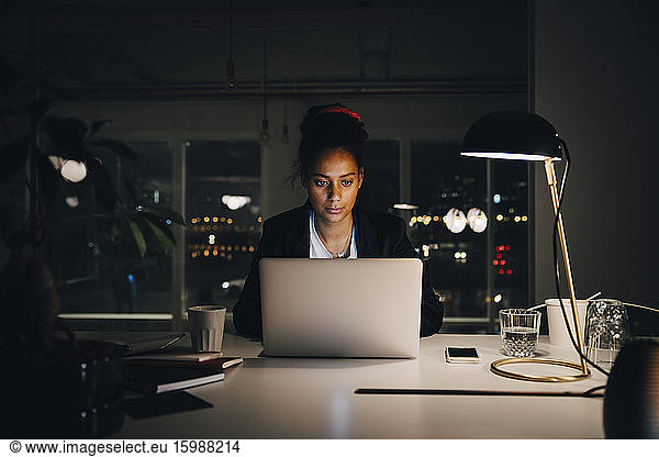 Dedicated young businesswoman working late while using laptop at creative office