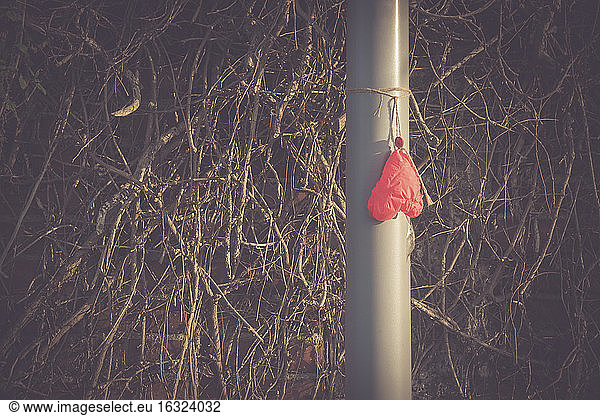 Deflated heart-shaped balloon hanging on a pole