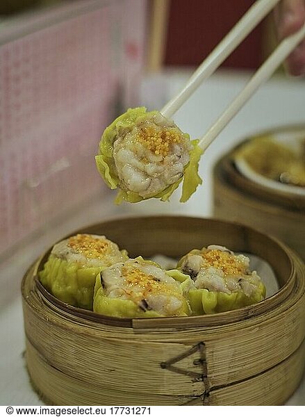 Delicious Chinese dim sum in a chinese restaurant  chopsticks holding steamed rice roll