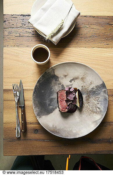 Delicious steak dish with modern plating on ceramic plate & wood table