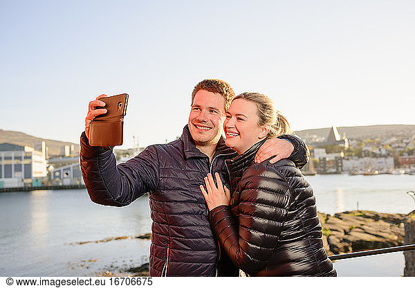 Delighted couple of tourists taking selfie at seafront